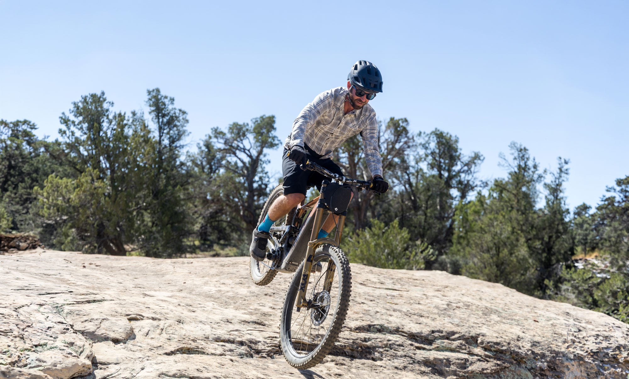 Person riding an e-mtb on a rocky trail with trees in the background